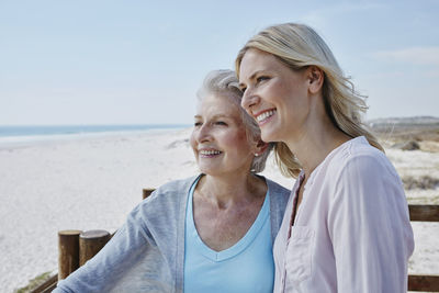 Smiling senior woman with adult daughter on the beach