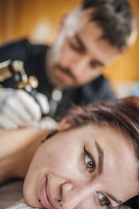 Male tattoo artist tattooing womans back in tattoo studio