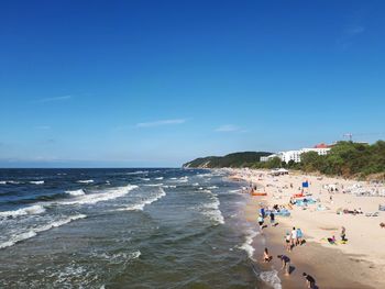 People on beach against blue sky