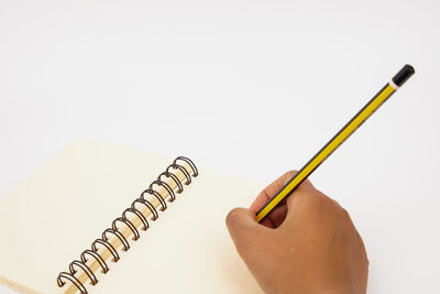 Close-up of hand holding book against white background