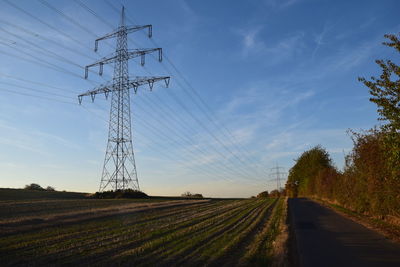 Electricity pylon on field against sky