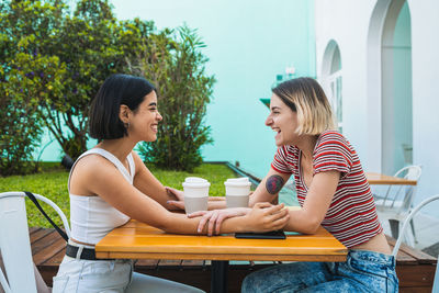 Smiling lesbians enjoying coffee on table