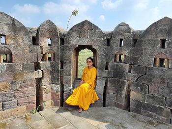 Full length of woman sitting by fort wall