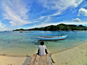 Rear view of man looking at sea against sky