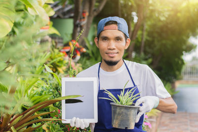 Portrait of smiling young man holding potted plant