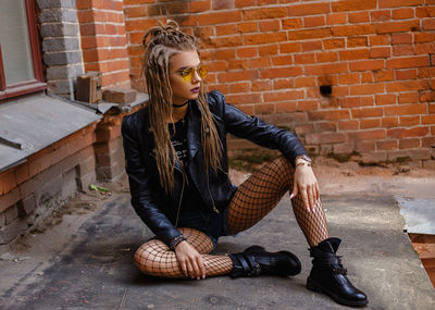 Young woman sitting on brick wall