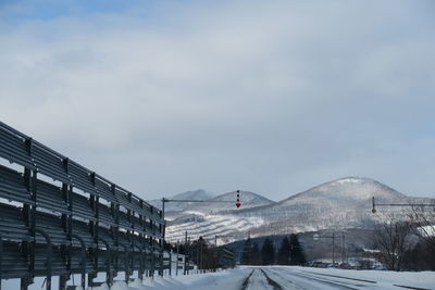 Snow covered road by buildings against sky