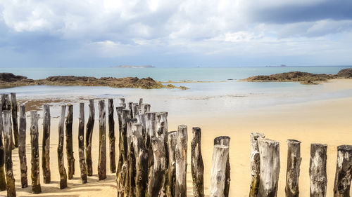 Panoramic view of wooden post on beach against sky