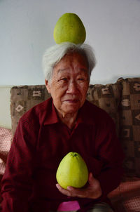 Portrait of happy senior woman with pummelos at home