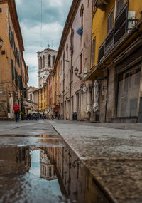 Wet street amidst buildings in city