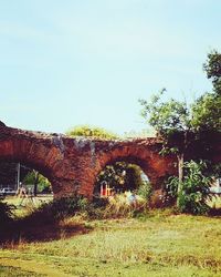 Arch bridge on field against clear sky