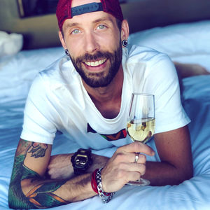 Portrait of smiling man holding champagne lying on bed