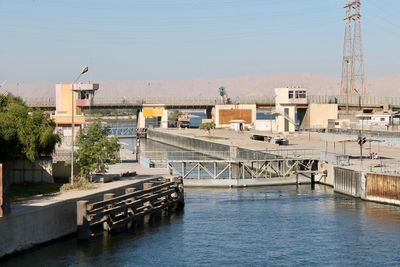 Bridge over river by buildings in city against clear sky