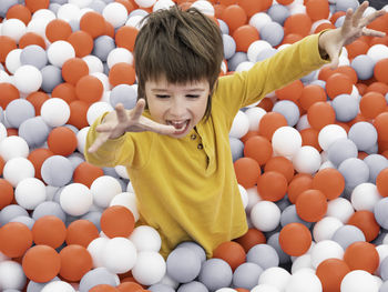 Happy boy plays in ball pit. plastic balls in dry paddling pool.leisure in playroom at kindergarten.