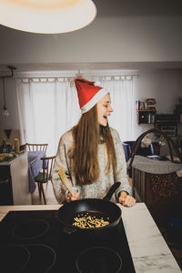 Rear view of woman holding food in kitchen