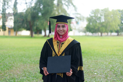 Portrait of smiling woman holding placard on field