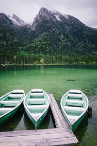 Boats moored on lake against mountains