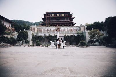 Rear view of woman standing by statue at historic temple