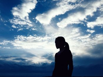 Silhouette woman standing against cloudy sky