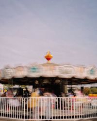 Blurred motion of people at amusement park against sky