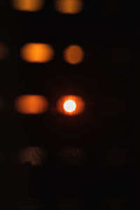 Defocused image of illuminated lights against sky at night