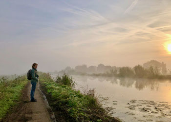 Side-view of woman looking over a canal in misty morning-light/