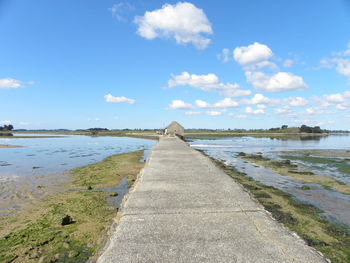 Footpath by sea against sky