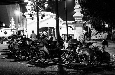 Bicycles on street against illuminated buildings in city