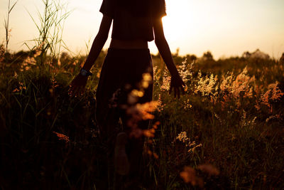 Silhouette woman standing on field against sky during sunset