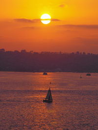 Silhouette sailboat sailing on sea against sky during sunset