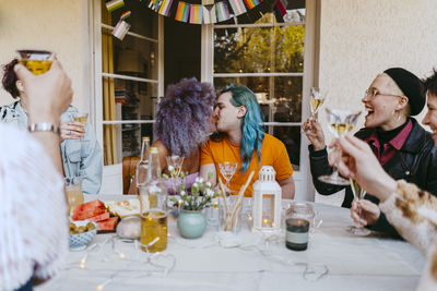 Romantic transwoman kissing gay friend during dinner party in back yard