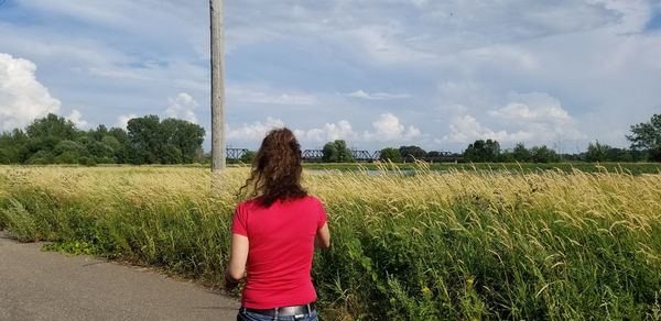 Rear view of woman standing on field against sky