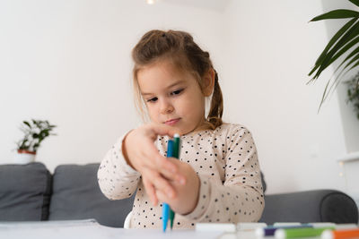 Portrait of cute preschooler child girl drawing with pencils at home