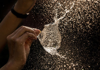 Cropped hand of person exploding water bomb