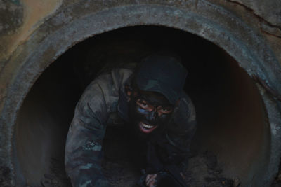 Portrait of smiling man with dirty face in concrete pipe