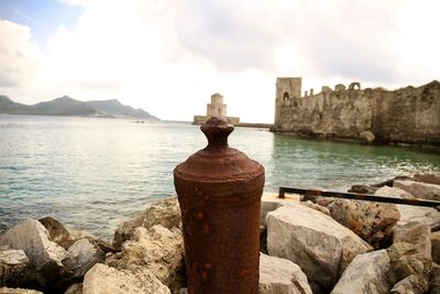 Close-up of rusty retaining wall by sea against sky