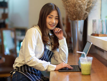 Portrait of a smiling young woman holding ice cream in cafe
