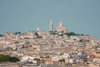 Buildings in city against clear blue sky