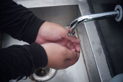 Close-up of hand holding water from faucet