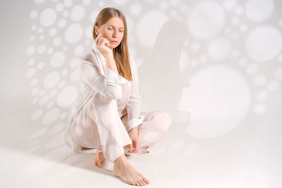 Portrait of young woman standing against white background