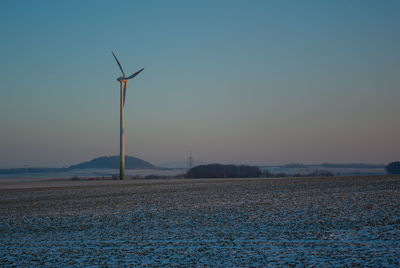 Wind turbines on field against sky during sunset