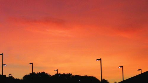 Silhouette street lights against orange sky