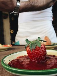 Strawberry in plate against man