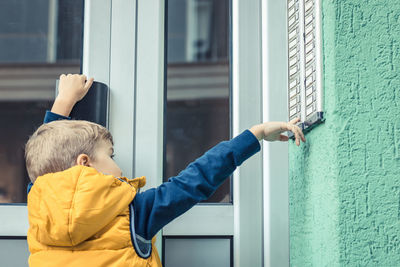 Rear view of boy ringing doorbell