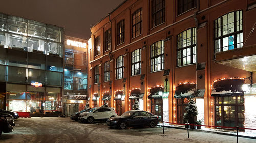 Cars on illuminated city against sky at night