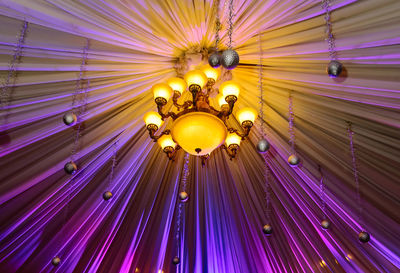 Low angle view of illuminated lighting equipment hanging on ceiling