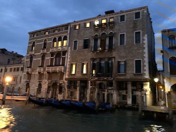 Canal amidst buildings in city at night