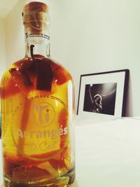 Close-up of beer bottle on table against wall