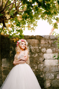 Bride looking away while standing against wall