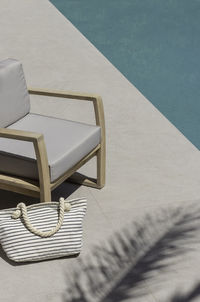 Swimming pool top angle view of seating area and striped summer bag with blue turquoise water